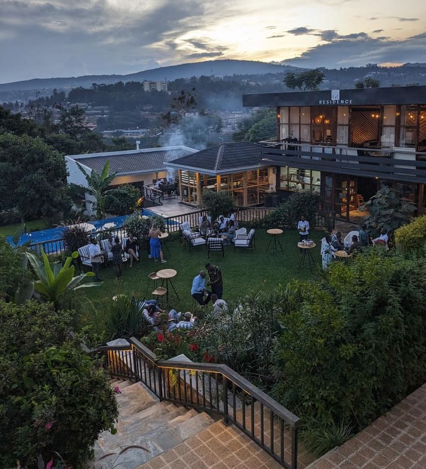 Imaara Bridge community members gathering at a hillside residence overlooking Kigali at dusk